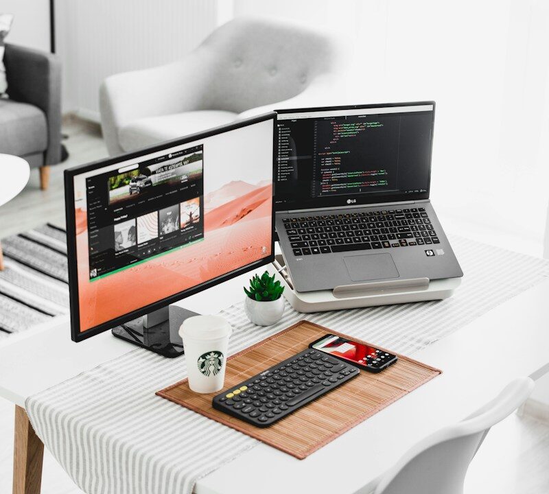 black flat screen computer monitor and laptop on table