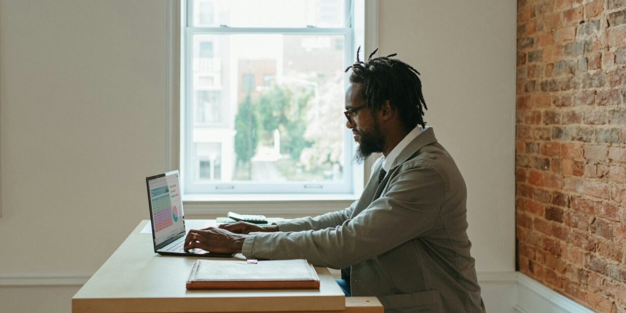 a person sitting at a desk with a laptop and papers