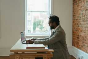 a person sitting at a desk with a laptop and papers