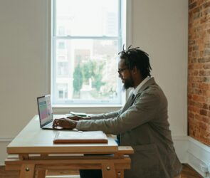 a person sitting at a desk with a laptop and papers